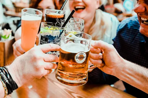 Bierkrüge und Gläser stoßen über dem Tisch zusammen