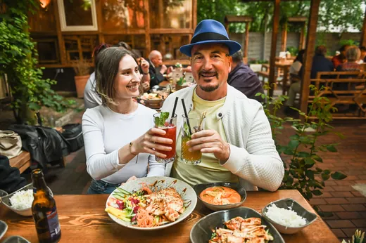 Ein Paar am Holztisch mit Getränken, Reis und gegrilltem Huhn