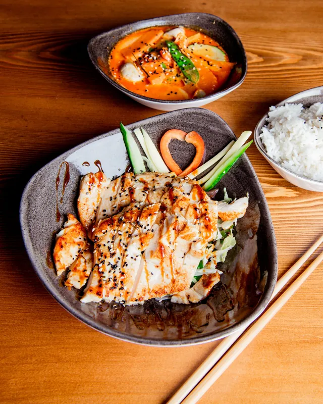 Gegrilltes Huhn mit Sesam, rotes Curry in einer Schale und Reis