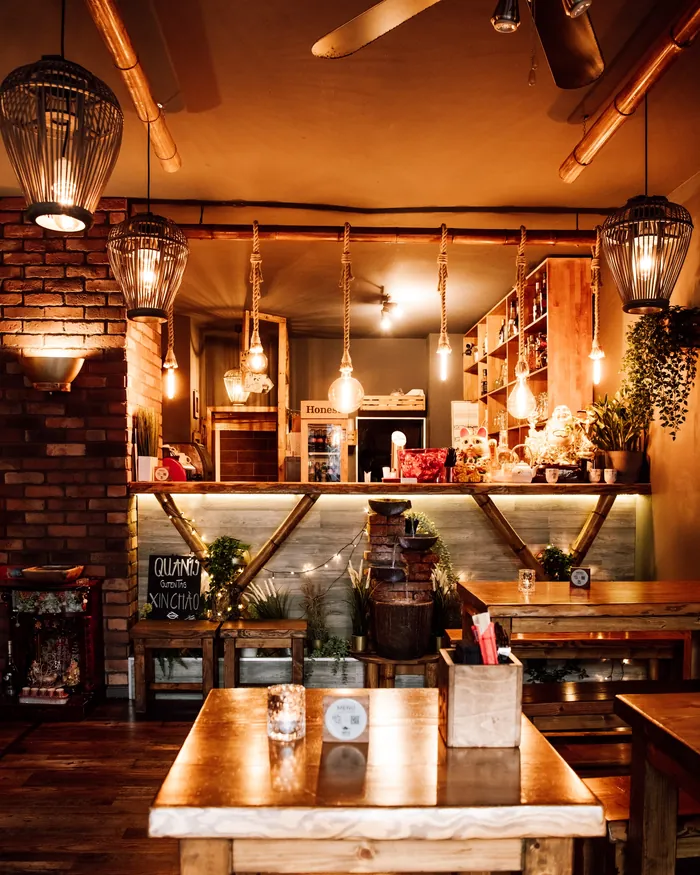 Bar im Quán 19 mit Glühbirnen an Seilen, Pflanzen und warmem Licht